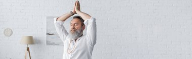 Beyaz gömlekli yaşlı sakallı adam kollarını kaldırıp meditasyon yapıyor ve dua eden eller, pankart