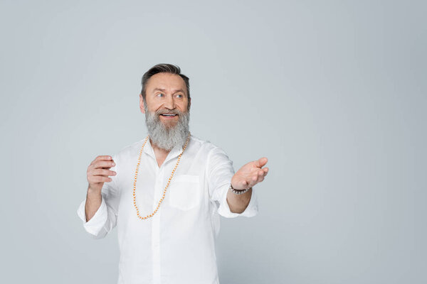 вдохновленный тренер, который смотрит в сторону и указывает рукой, изолированной от серого