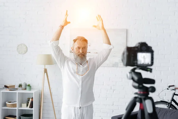 stock image spiritual guru with raised hands near shining aura and blurred digital camera