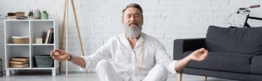 Sakallı usta guru, kapalı gözlerle dua ederken çenesini gösteriyor.