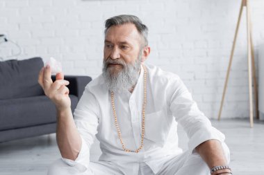 Boncuklar içinde kıdemli ruhani guru evde selenit kristalle meditasyon yapıyor. 
