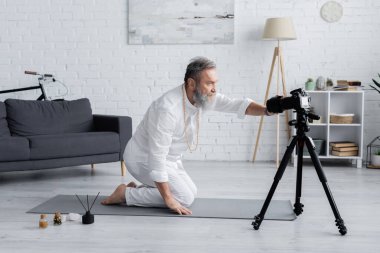 Yoga hocası dijital kamerayı aroma çubukları ve aromalı yağların yakınına ayarlıyor.