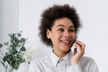 Mutlu Afro-Amerikalı kadın evde akıllı telefondan konuşuyor.