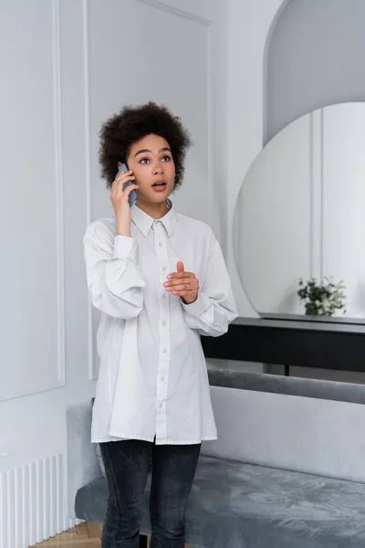 Donna Afro Americana Scioccata Che Parla Telefono Cellulare Soggiorno Moderno — Foto Stock