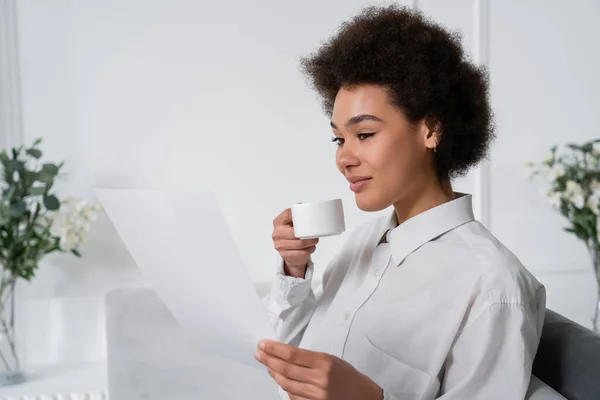 Mujer Afroamericana Rizada Sosteniendo Una Taza Café Mientras Mira Documento — Foto de Stock