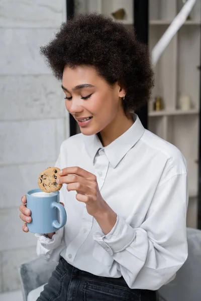 Szczęśliwy Afroamerykanka Kobieta Gospodarstwa Filiżanka Mleka Ciasteczka Chipsami Czekoladowymi — Zdjęcie stockowe
