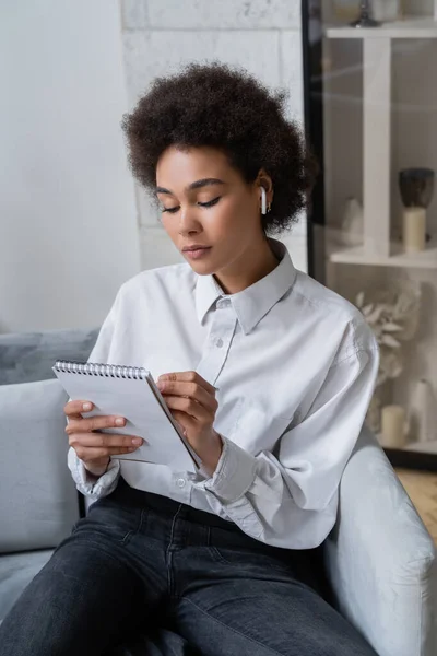 Mujer Afroamericana Rizada Camisa Blanca Auriculares Inalámbricos Haciendo Notas Cuaderno — Foto de Stock