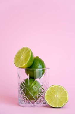 Pembe arka planda yeşil ve taze limonlar.