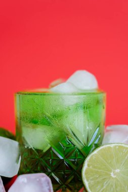 Donmuş buz küplerini cam içinde, yeşil mojito ve kırmızı üzerine limon ile kapatın.