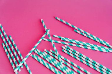 Pembe arkaplanda çizgili mavi ve beyaz pipetlerin üst görünümü
