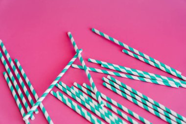 top view of striped blue and white straws on pink background clipart