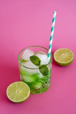 Camda donmuş buz küplerinin yüksek açılı görüntüsü ve pembe üzerinde yeşil mojito içeceği. 