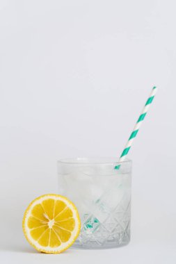 Buz küplü soğuk bardak ve dilimlenmiş limonun yanında kağıt kamış.