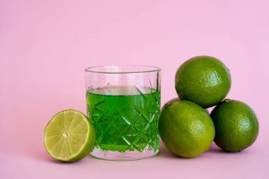 Alkolün yanındaki yeşil taze limonlar, pembe camlar içinde.