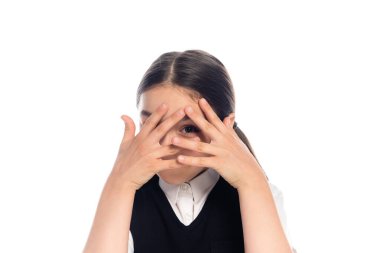Schoolkid covering face and looking at camera isolated on white  clipart