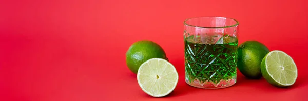 Bebida Alcohólica Verde Vidrio Facetado Cerca Limas Agrias Rojo Bandera — Foto de Stock