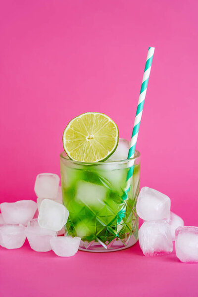 кубики льда в огранённом стекле с напитком мохито и нарезанной известью на розовом 