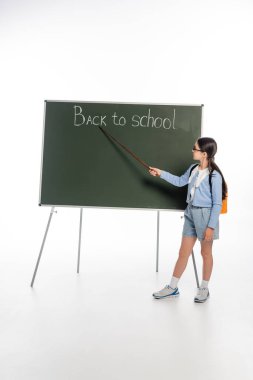 Okula yakın bir yerde elinde işaretle beyaz arka planda karatahtaya yazı yazan okul çocuklarının yan görüntüsü