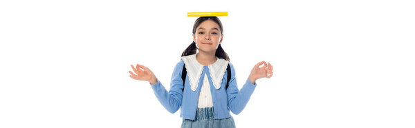 Positive schoolkid with book on head and backpack showing om mudra gesture isolated on white, banner 