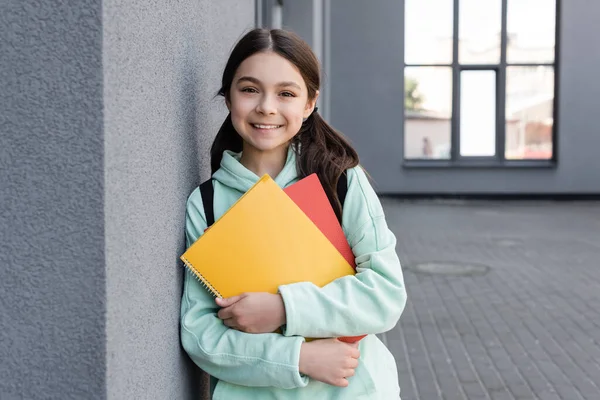 Cheerful Schoolgirl Holding Notebooks Looking Camera Building Outdoors — Stockfoto