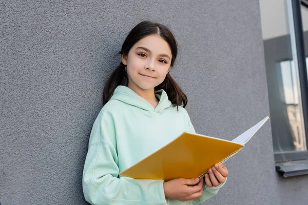 Escolar Sonriente Sosteniendo Cuaderno Mirando Cámara Cerca Del Edificio Aire —  Fotos de Stock