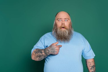 discouraged overweight man pointing at himself and bulging eyes isolated on green