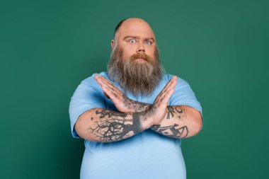 tense plus size man showing refuse gesture with crossed arms isolated on green