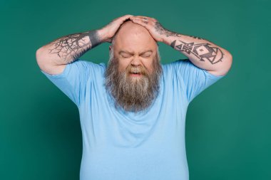 upset bearded man with overweight touching bald head isolated on green clipart