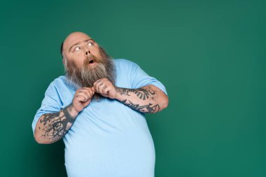 scared overweight man with beard looking away isolated on green