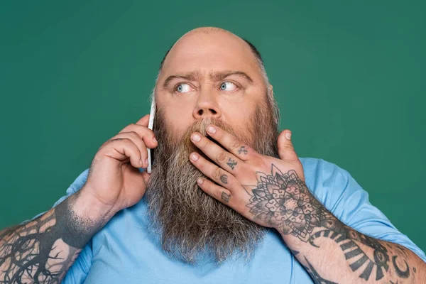 Shocked Tattooed Man Covering Mouth Hand While Talking Smartphone Isolated — ストック写真