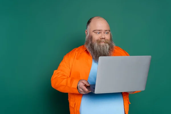 Bearded Positive Man Overweight Looking Laptop Isolated Green — Photo