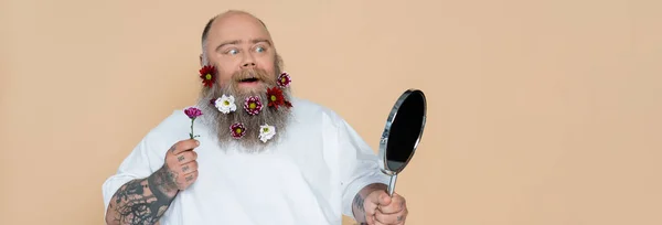 Impressed Overweight Man Floral Decor Beard Looking Mirror Isolated Beige — Stok fotoğraf