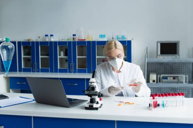 Researcher in white coat working with test tube and petri dish in laboratory  clipart