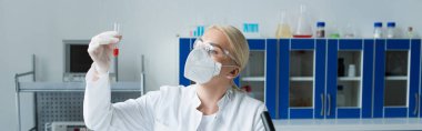 Scientist in protective mask holding test tube in laboratory, banner 