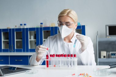 Laboratuvarda antijen ve maymun çiçeği harfleriyle test tüpleri tutan bir bilim adamı. 