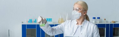 Scientist in white coat holding flask and digital tablet in lab, banner 