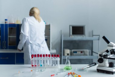Back view of scientist working near test tubes with monkeypox lettering and microscope in lab 
