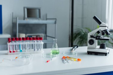 Test tubes with monkeypox lettering near flask and microscope in lab 