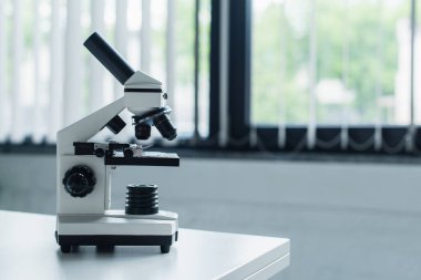 Microscope on white table in blurred laboratory 