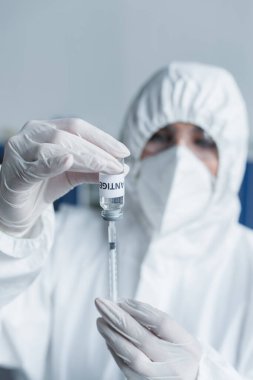 Laboratuvarda antijen ve şırınga tutan lateks eldivenli bulanık bilim adamı