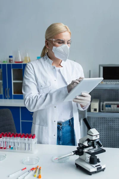 Cientista Máscara Protetora Usando Tablet Digital Perto Tubos Ensaio Microscópio — Fotografia de Stock