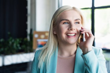 Huzur odasında akıllı telefondan konuşan neşeli bir psikolog. 