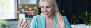 Smiling psychologist having video call on smartphone in consultation room, banner 