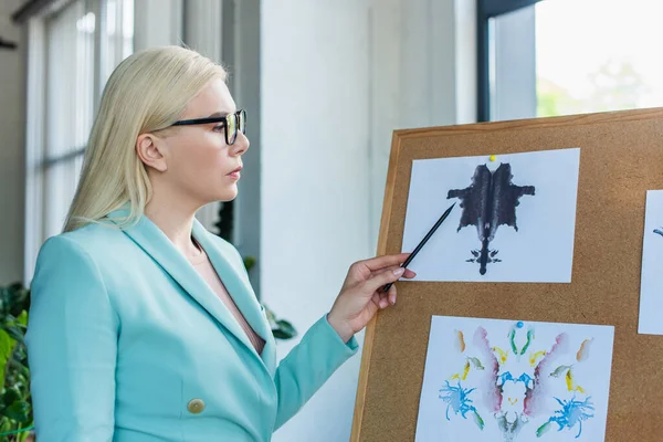 Side view of psychologist pointing at Rorschach test in consultation room 