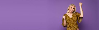 happy blonde woman in blouse having menopause and rejoicing on purple, banner