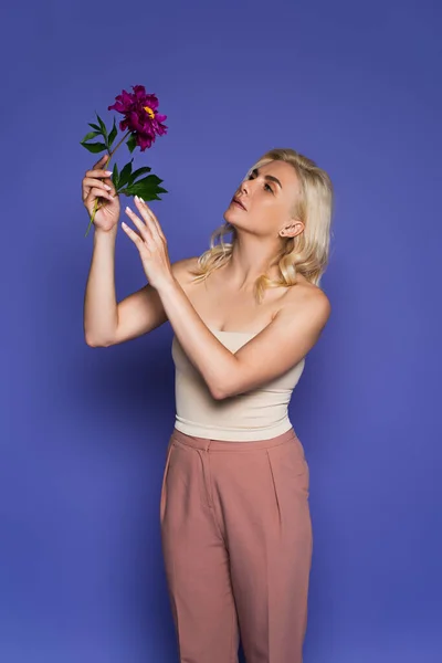 Femme Blonde Aux Épaules Nues Regardant Fleurir Fleur Sur Violet — Photo
