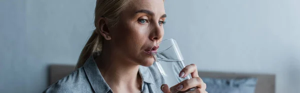 blonde woman with menopause drinking fresh water from glass, banner