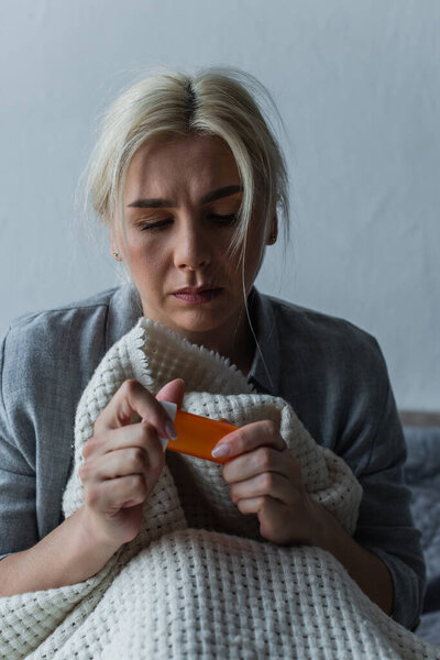 sad woman with climax holding bottle with painkillers 