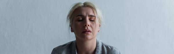 sad blonde woman with climax and closed eyes at home, banner
