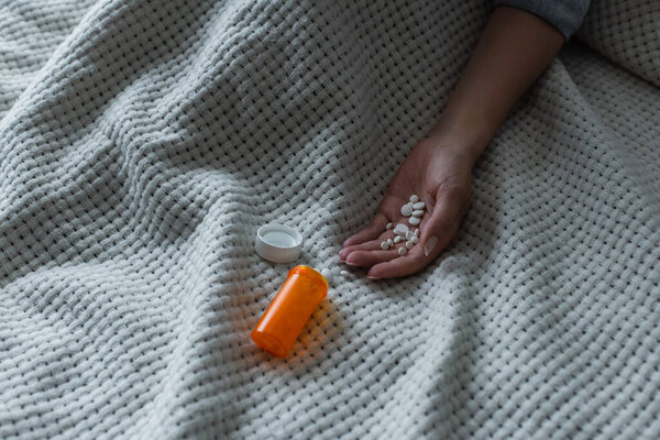 cropped view of depressed woman with climax holding pills in hand 